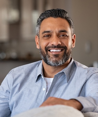 Man in blue shirt smiling on couch