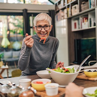 Woman smiling while eating healthy meal at home