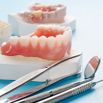 Dentures on a plaster base next to dental instruments