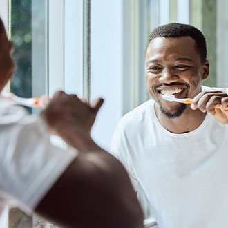 Man smiling while brushing his teeth