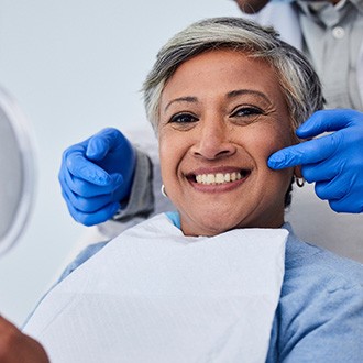 Woman smiling while holding handheld mirror