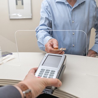 A man using a credit card to pay the cost of dentures