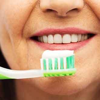 closeup of a person smiling with a toothbrush with toothpaste