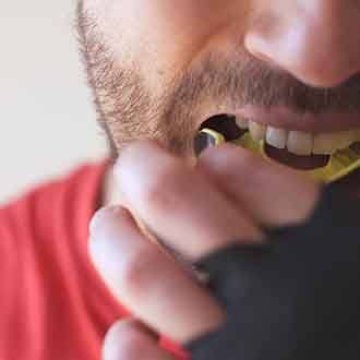 closeup of a man putting a mouthguard in his mouth before boxing