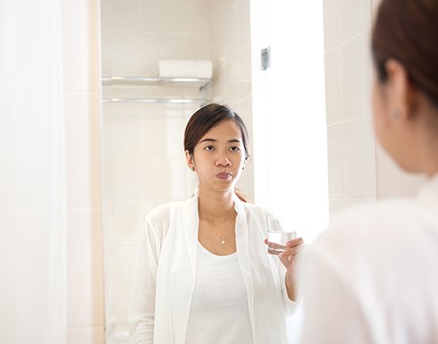 a woman swishing salt water in her mouth