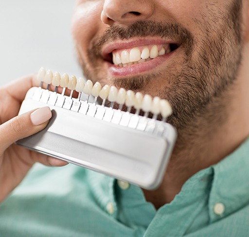 Dentist looking at patient's teeth and shade scale